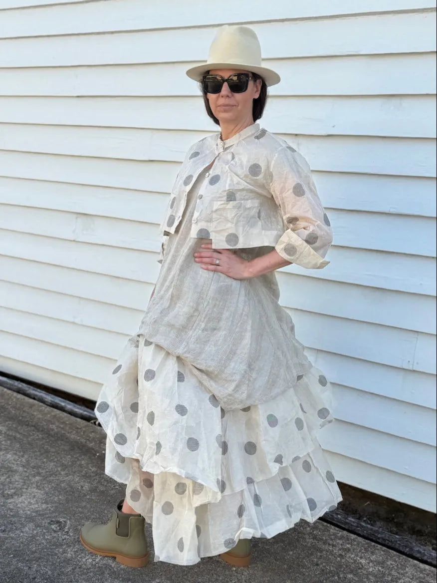 Person wearing Dogstar a layered outfit with polka dot patterns against a white wall.