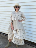 Person wearing a layered outfit with polka dot and plain pieces, standing against a white wall.