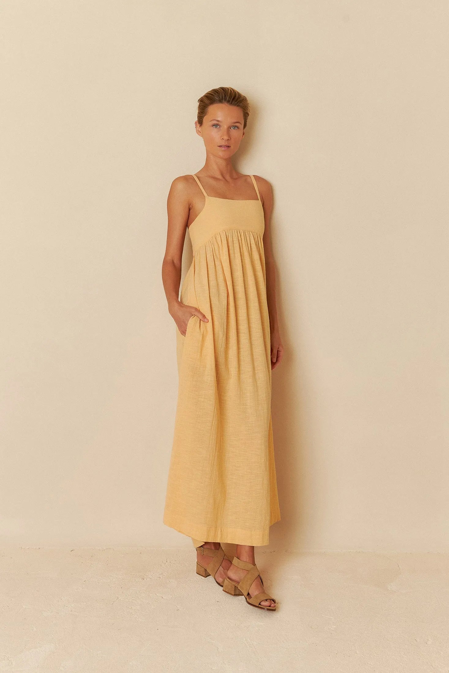 Woman wearing a yellow dress against a beige background