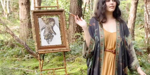 Woman in a Market of Stars Kimono forest holding a painting of a child on an easel